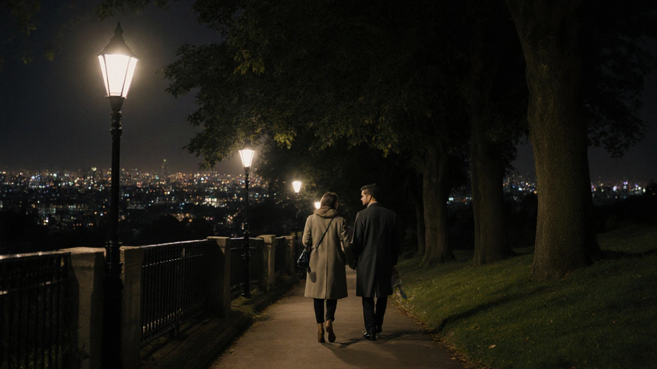 A couple walking peacefully along a tree-lined London path at night, calm and unobserved under streetlamps.
